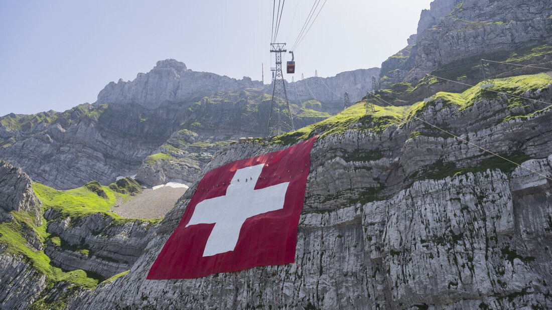 Kleine Männchen auf grosser Fahne: Die grösste Schweizerflagge wird entrollt. (Bild Gian Ehrenzeller/Keystone)