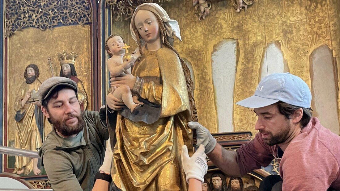 Teamarbeit: Guido Keller (links) und Claudio Büchler von der Firma Bianchi Bildhauer setzen in der Kirche St. Calixtus in Brienz/Brinzauls die Marienfigur mit Jesuskind in den Schrein ein. (Bild: Daria Schenk)