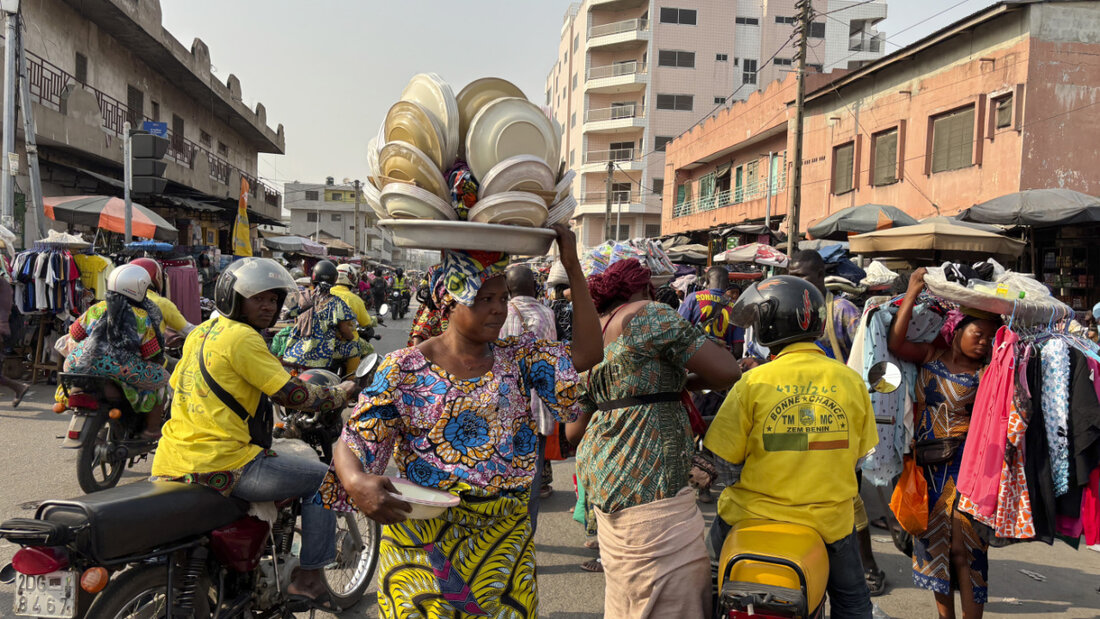 ARCHIV - Eine Tellerverkäuferin macht sich auf den Weg zum Markt in Cotonou. Foto: Sunday Alamba/AP/dpa 20251207162400348.jpg