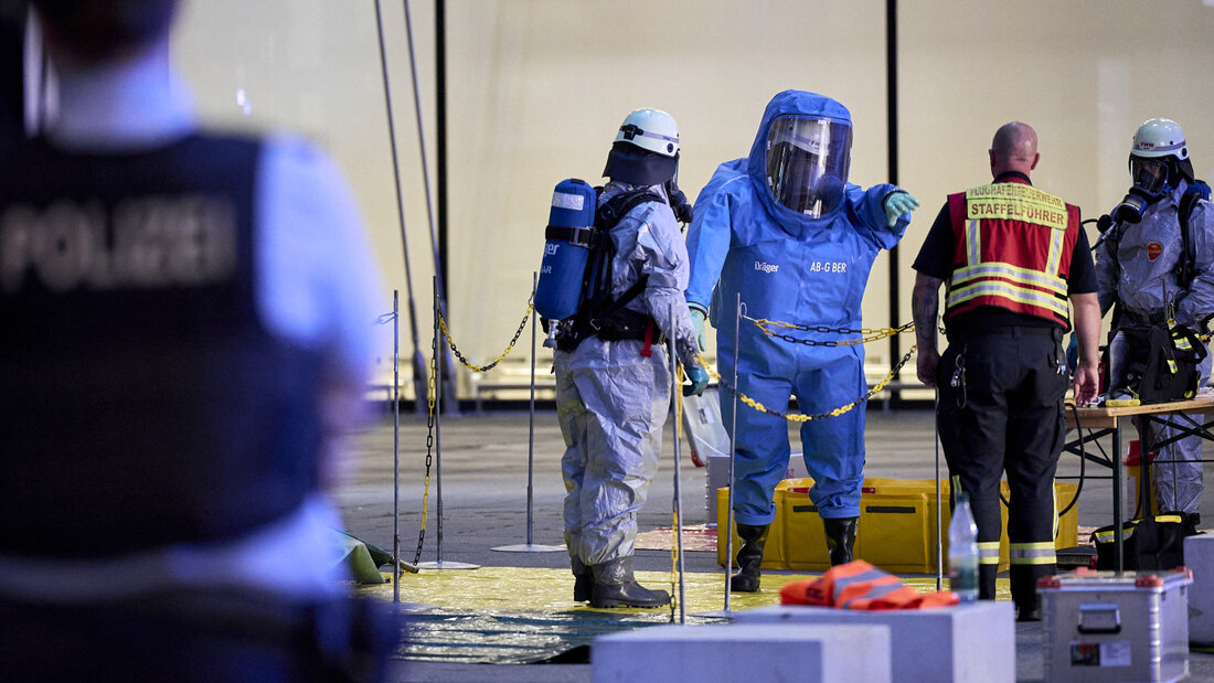 Ein Mitglied der Feuerwehr in einem Chemikalienschutzanzug wird von einem Kollegen vor dem Terminal 1 am Flughafen BER dekontaminiert. Foto: Michael Ukas/dpa 20260903215847949.jpg