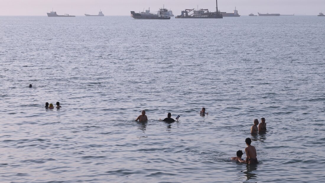 dpatopbilder - Anwohner schwimmen, während Fracht- und Handelsschiffe in der Straße von Hormus vor Bandar Abbas im Iran vor Anker liegen. Foto: Amirhosein Khorgooi/ISNA/AP/dpa 20260809042830479.jpg
