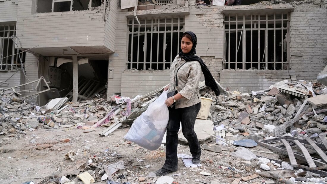 ARCHIV - Eine Frau holt Kleidung in einer Tüte aus einem Wohnhaus, das am vergangenen Montag (09.03.2026) während der US-israelischen Luftangriffe beschädigt wurde. Foto: Vahid Salemi/AP/dpa 20260316090712489.jpg