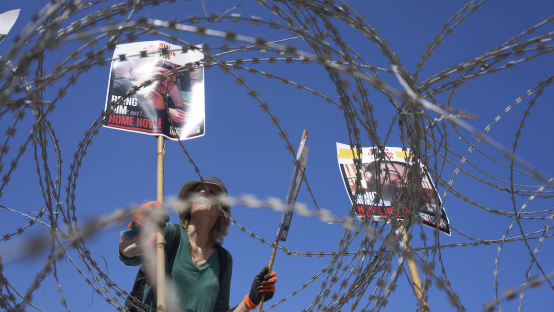 dpatopbilder - Eine Frau platziert Bilder der Geiseln Nimrod Cohen (l) und Eitan Horn, die von der Hamas im Gazastreifen gefangen gehalten werden, auf einem Stacheldraht während eines Protestes von Familien auf dem Platz der Geiseln. Foto: Ariel Schalit/AP/dpa 20250803025531907.jpg