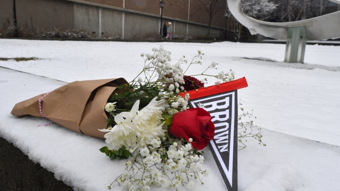 Ein Blumenstrauß liegt auf dem Schnee auf dem Campus der Brown University. Foto: Steven Senne/FR172182 AP/AP/dpa 20251215074006128.jpg