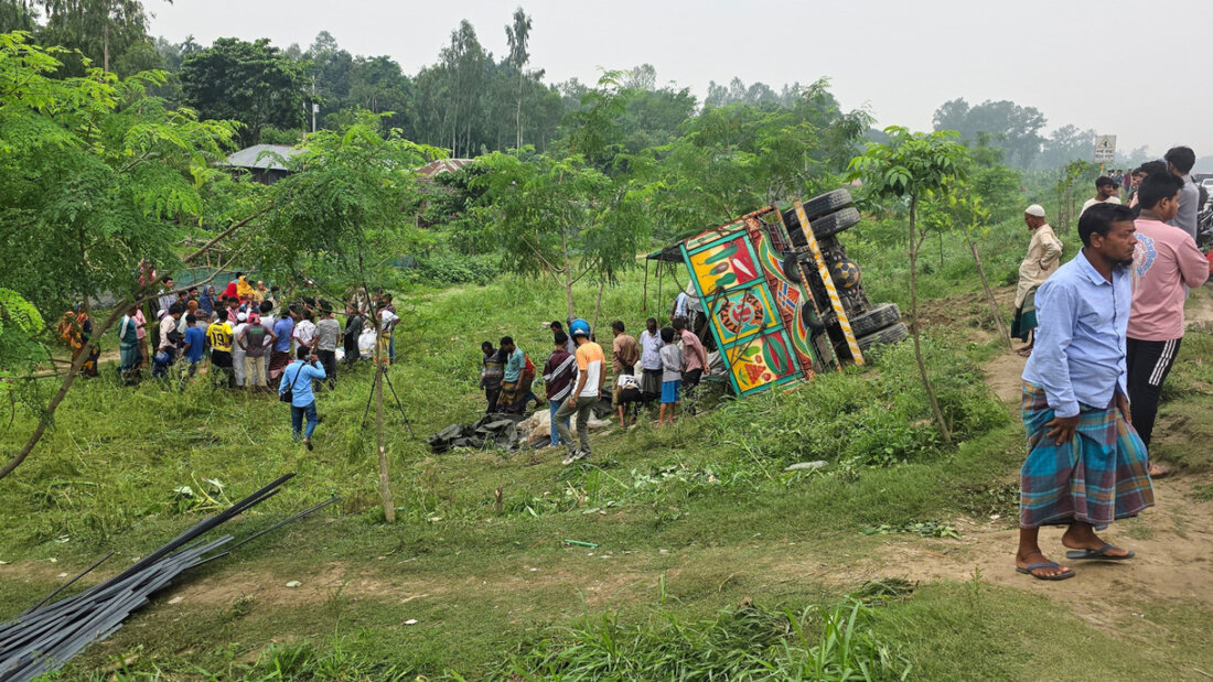 Menschen schauen zu, nachdem ein mit Eisenstangen und zusätzlichen Passagieren beladener Lastwagen auf einer Straße umgestürzt ist. Foto: Sohel Talukder/AP/dpa 20260525113445408.jpg