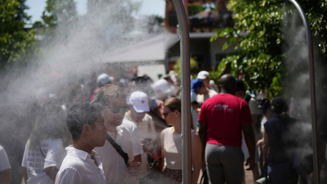 French Open-Besucher kühlen sich an einem heißen Tag mit Wasser aus Sprinklern ab. Foto: Christophe Ena/AP/dpa 20260526114137153.jpg