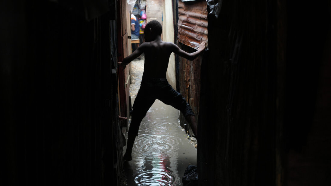 Ein Junge bewegt sich in einer vom Regen des Hurrikans «Melissa» überfluteten Gasse in einer Notunterkunft für Familien, die durch Bandengewalt vertrieben wurden. Foto: Odelyn Joseph/AP/dpa 20251120124614401.jpg