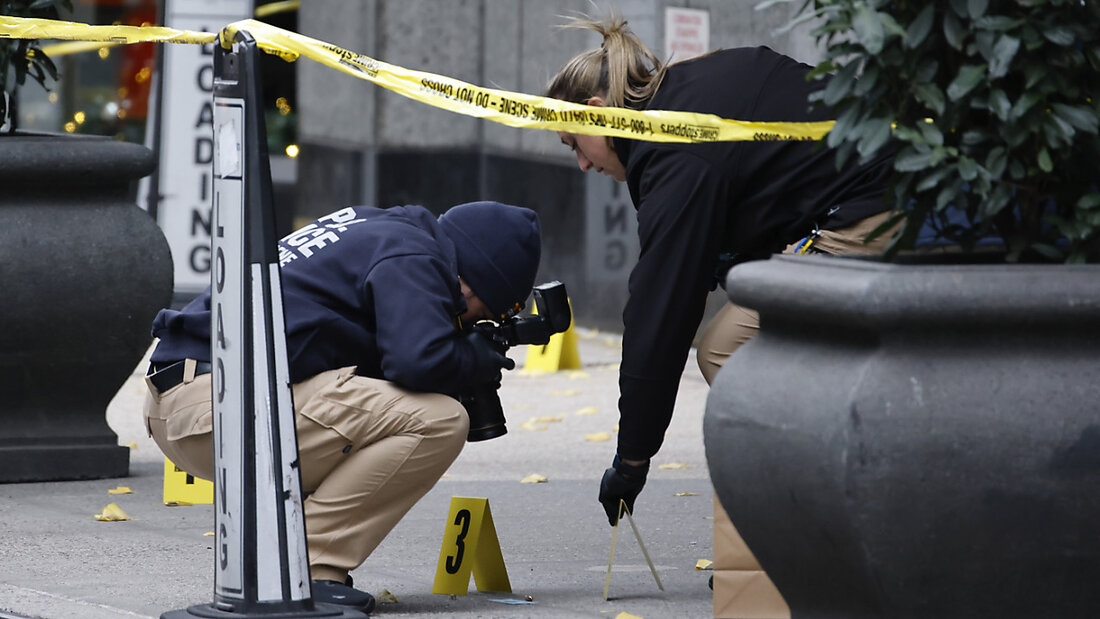 ARCHIV - Mitglieder der New Yorker Polizei fotografieren Kugeln, die auf dem Bürgersteig liegen, während sie einen Tatort am Eingang Hauses in der Nähe des Times Square untersuchen. Foto: Stefan Jeremiah/FR171756 AP/dpa 20241210123630234.jpg