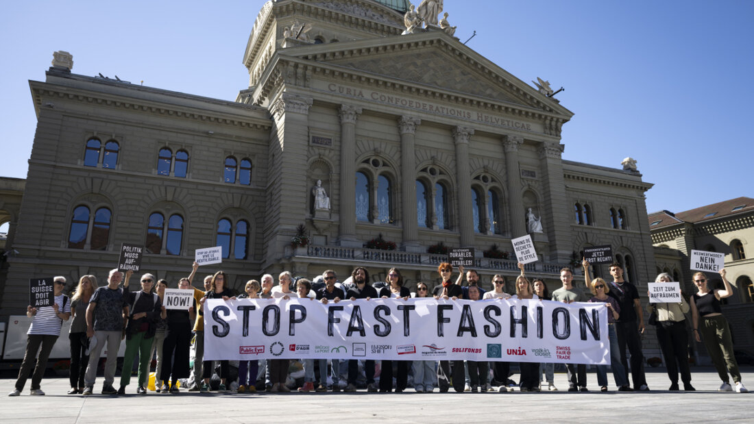 Freiwillige posieren am Mittwoch mit Plakaten und einem Transparent vor einem Berg von Kleidersäcken gegen Fast Fashion. 20250903115232215.jpg