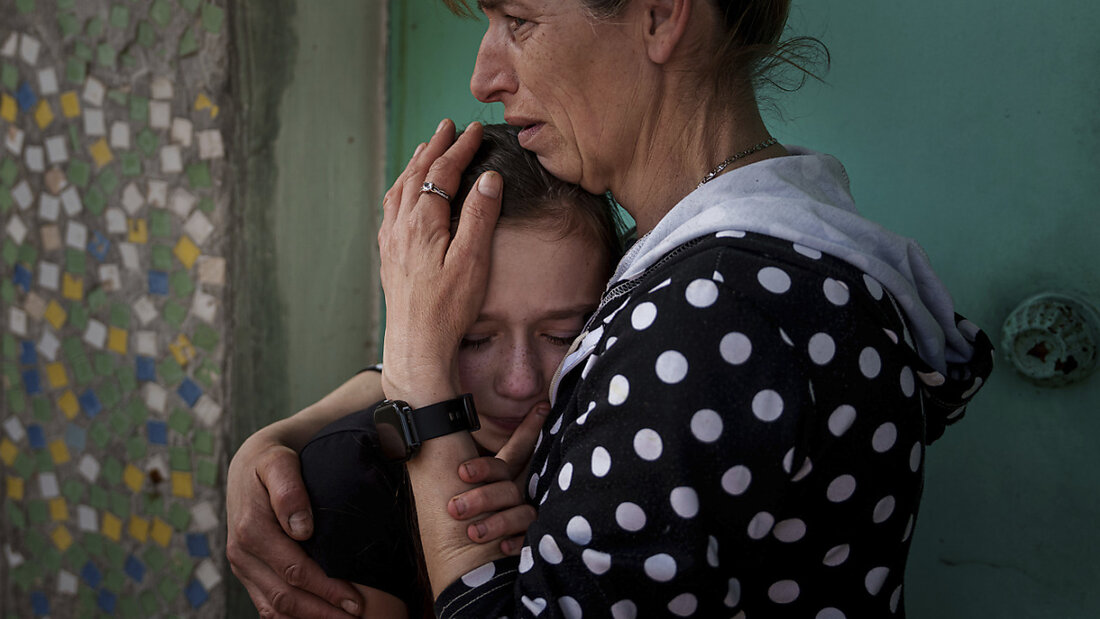 Eine Mutter weint mit ihrer Tochter während der Trauerfeier für Maksym Martynenko, der bei einem russischen Angriff auf Sumy getötet wurde. Foto: Evgeniy Maloletka/AP/dpa 20250418143847838.jpg