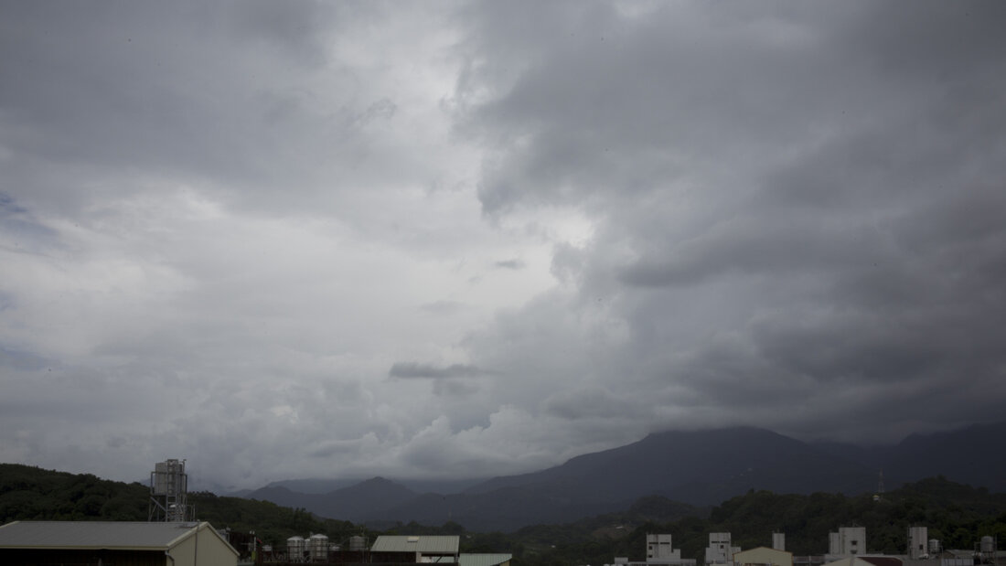 Dunkle Wolken hängen über Bergen und Gebäuden am Stadtrand. Taiwan bereitet sich auf den Taifun «Bavi» vor. Foto: Andre M. Chang/ZUMA Press Wire/dpa 20260710120001008.jpg