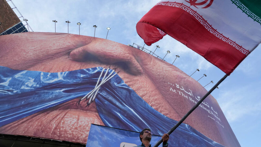 ARCHIV - Ein Mann schwenkt in Teheran eine iranische Flagge vor einer Plakatwand mit einer Darstellung der Straße von Hormus und zugenähten Lippen von US-Präsident Trump. Foto: Vahid Salemi/AP/dpa/Archivbild 20260512213418112.jpg